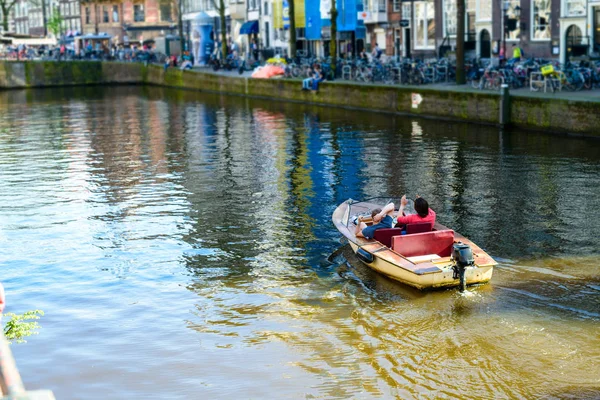 Two persons floating on the boat on the river Amstel in Amsterda