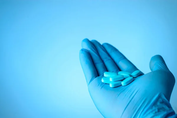 Pastillas azules en los médicos mano sobre fondo azul con copyspace. Li. — Foto de Stock