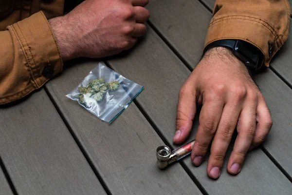 Hands of unidentified addict with cannabis in plastic bag on the — Stock Photo, Image