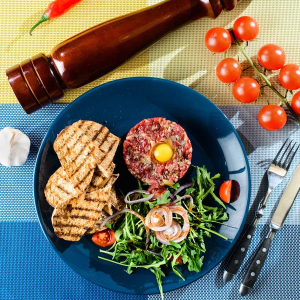 盘与牛肉鞑靼, 西红柿和叶子在桌与 kn — 图库照片