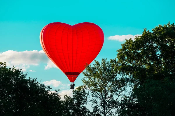 Bright red hot air balloon in the shape of heart against blue sk — Stock Photo, Image