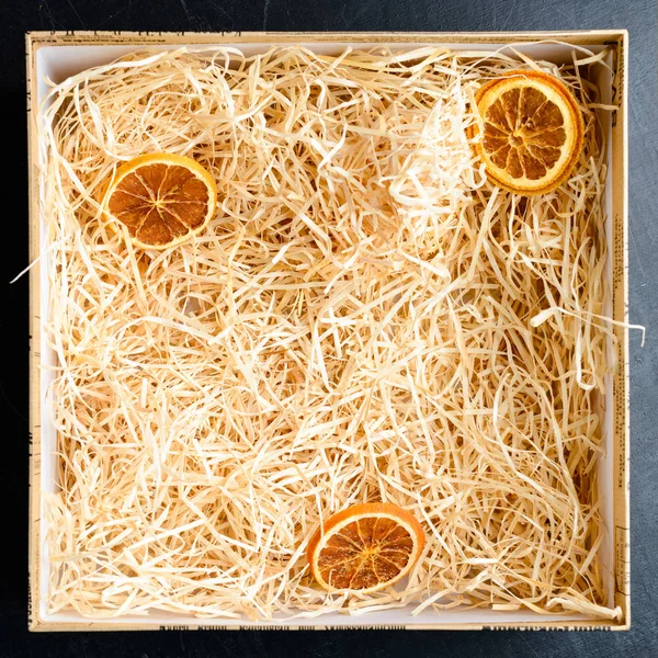 Composition with decorative straw and citrus in a box, close-up.