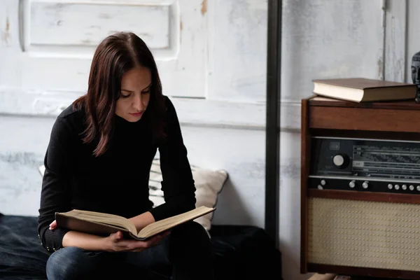 Caucasian pretty brunette woman sitting and reading a book indoo