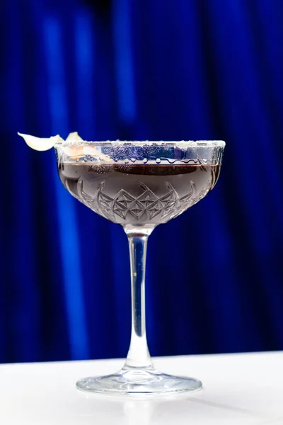 Schwarzer alkoholischer Cocktail im Martini-Glas auf blauem Hintergrund, — Stockfoto