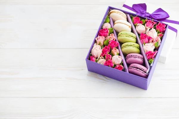 flowers in a box with a macaroon on a wooden background with spa