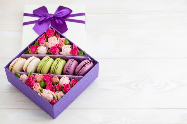 flowers in a box with a macaroon on a wooden background with spa