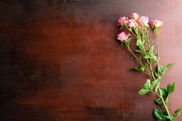 Φρέσκα ροζ τριαντάφυλλο λουλούδια σε αφηρημένα φόντο ένα ξύλινο τραπέζι — Φωτογραφία Αρχείου
