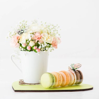 bir bardak ve bir plaka üzerinde macaroons çiçeklenir