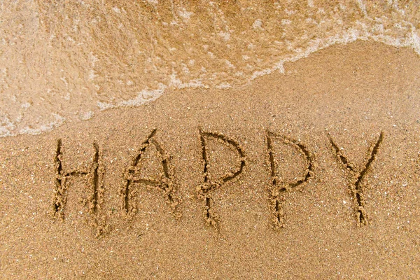 Слово счастливое, написанное на песке — стоковое фото