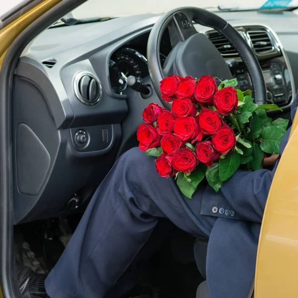 man in car with roses