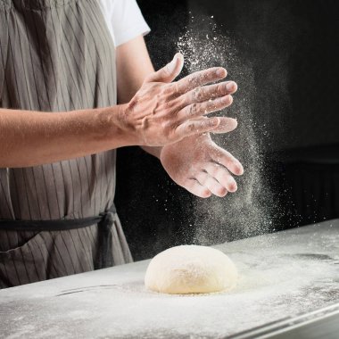 kadın baker rulo hamur ahşap oyun tahtası üzerinde un serpilir. Pro
