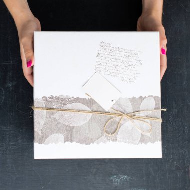 bir hediye ile kare şeklinde bir kutu üzerinde tutan eller