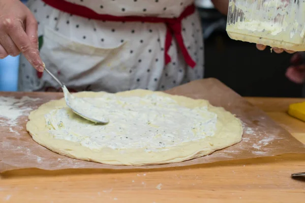 Massa de pizza com molho branco. Chef feminino adicionando alguns cogumelos . — Fotografia de Stock