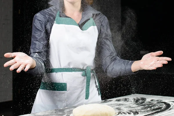 woman baker sprinkled flour on roll dough on a wooden board. Pro