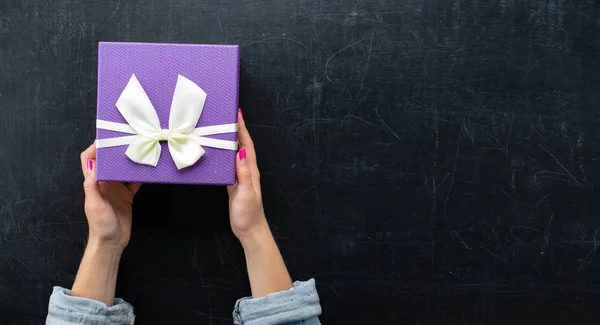 Manos femeninas sosteniendo una caja en forma de corazón con un regalo — Foto de Stock