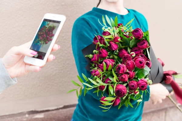 woman shooting a photo of another woman with bouquet of bright p
