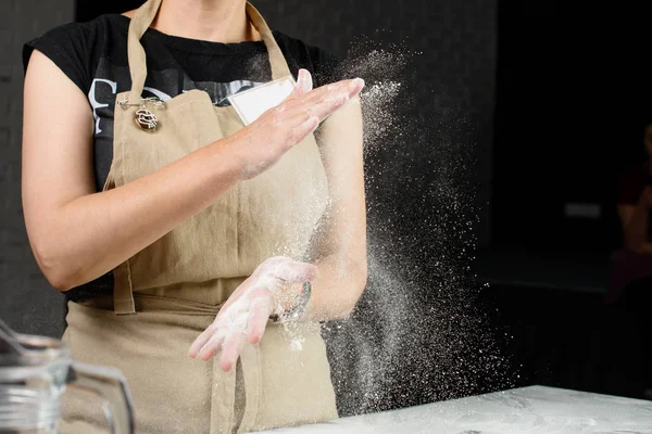 woman baker sprinkled flour on roll dough on a wooden board. Pro