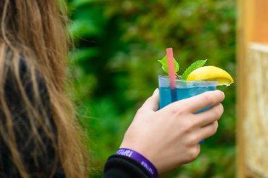 bir cam ile mavi soğuk yaz kokteyl açık havada tutan kadın s