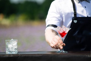 bir martini cam kırmızı soğuk cocktai ile tutarak yakın çekim barmen