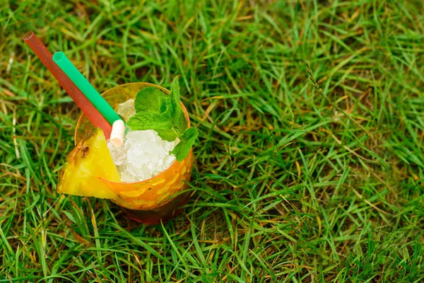 Vaso con cóctel frío amarillo fresco de verano en hierba al aire libre , — Foto de Stock