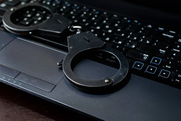 steel police handcuffs lying on keyboard. Concept of internet cr