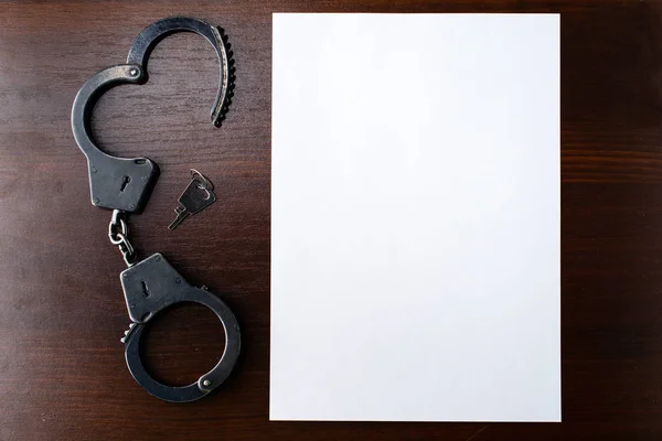 Steel police handcuffs and empty sheet of paper frame for yo — Stock Photo, Image