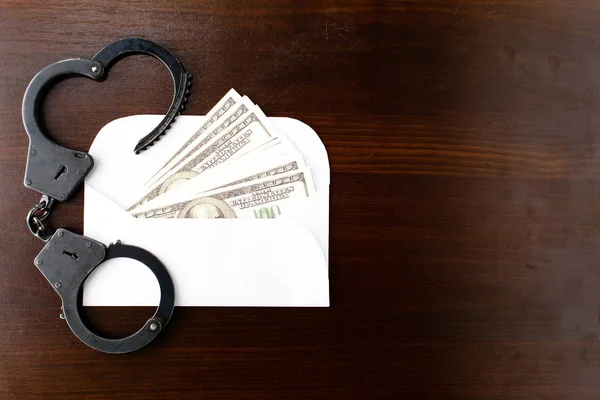 El sobre con dinero en dólares y esposas de la policía de acero en wo —  Fotos de Stock