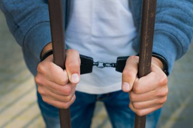 bir işadamı bir cezaevi parmaklıklar arkasında elleri kelepçeli. H