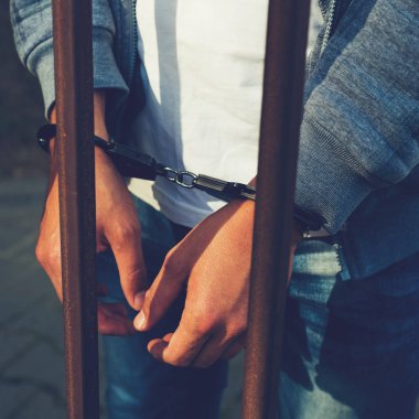 bir işadamı bir cezaevi parmaklıklar arkasında elleri kelepçeli. C