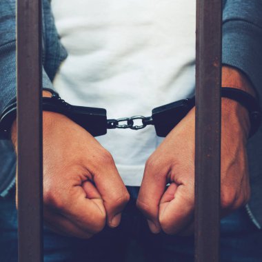 bir işadamı bir cezaevi parmaklıklar arkasında elleri kelepçeli. C
