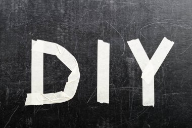DIY kelimenin üstten görünüm koyu arka plan üzerinde yapışkan bant ile yapılan,