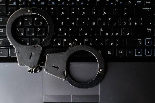 steel police handcuffs lying on keyboard, top view. Concept of i