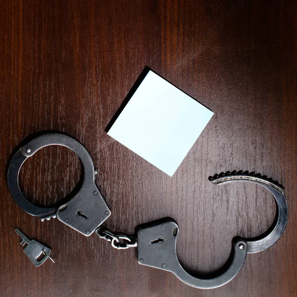 Стальные полицейские наручники и пустой лист бумажной рамы для вас — стоковое фото