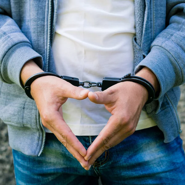 Un joven criminal esposado, al aire libre. Concepto de delito —  Fotos de Stock