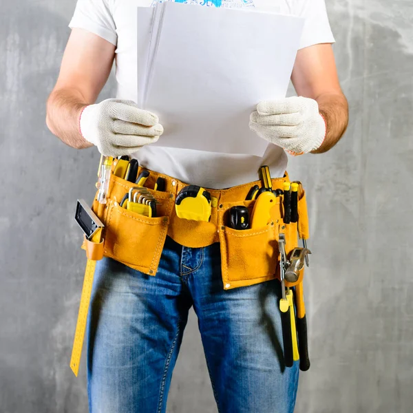 unidentified handyman standing with a tool belt with constructio