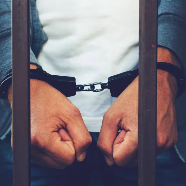 Руки бизнесмена в наручниках за решеткой тюрьмы. C — стоковое фото
