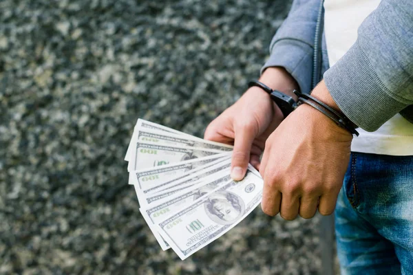 Arrested rowdy in handcuffs counting dollar banknote. Arrested f — Stock Photo, Image