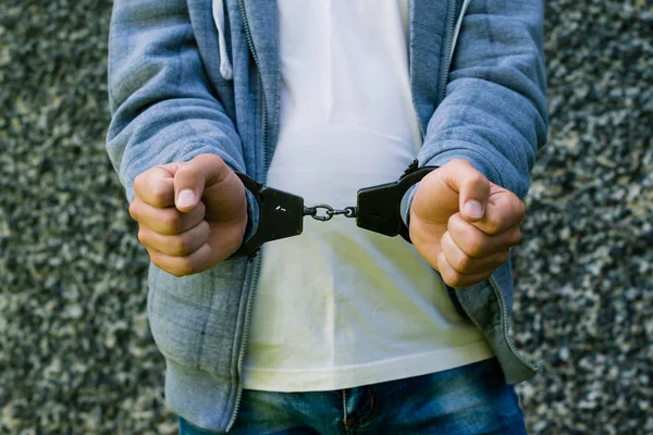 Молодий злочинець стоїть в наручниках, на відкритому повітрі. Концепція злочину — стокове фото