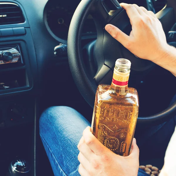 Betrunkener sitzt am Steuer eines Autos und trinkt Alkohol — Stockfoto