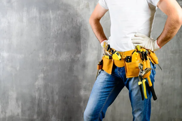 Unknown handyman with hands on waist and tool belt with construc — Stock Photo, Image