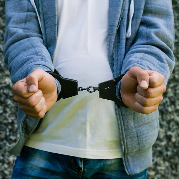 Молодий злочинець стоїть в наручниках, на відкритому повітрі. Концепція злочину — стокове фото