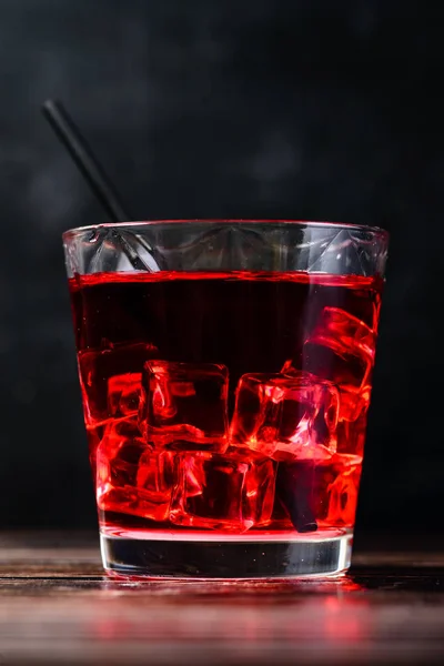 Top view of glass of red cocktail with ice cubes and straw on da — Stock Photo, Image