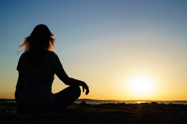 kadın yoga uygulamaları ve lotus pozisyonu üzerinde derin derin düşünür 