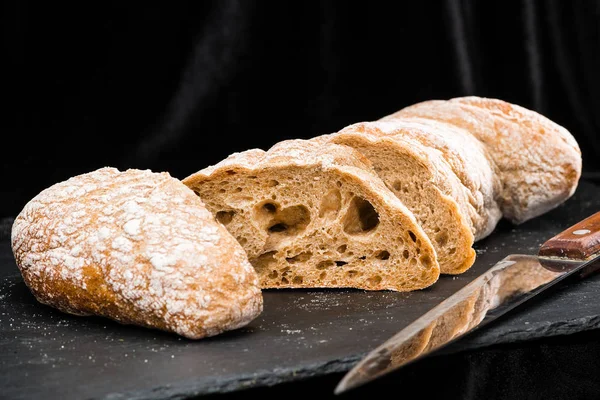 Selective focus on fresh sliced warm homemade bread on dark back — Stock Photo, Image