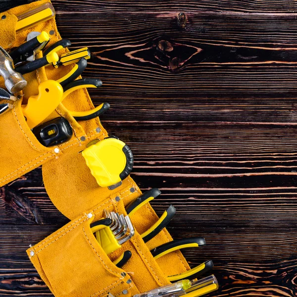 Läder gul verktygsbälte med verktyg på brunt trä — Stockfoto
