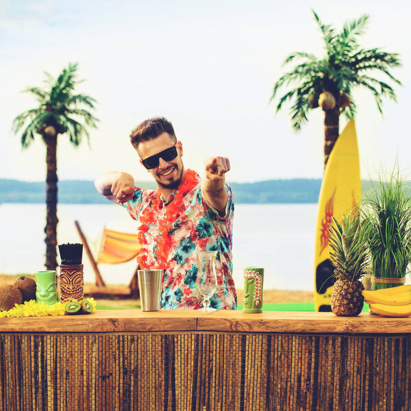 Handsome bartender standing near the bar counter and showing fin