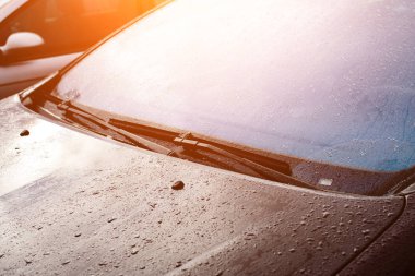 Cam silecekleri ışınları içinde yağmur sonra damla ile gri bir araba