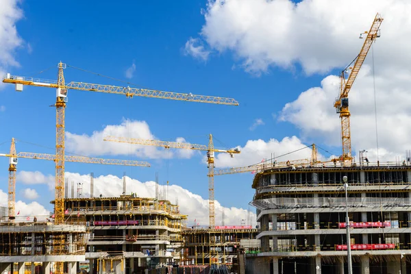 Construction site with cranes and buildings against blue sky. Hi — Stock Photo, Image