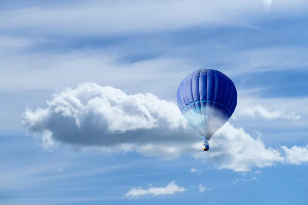 Hot air blue ballon against blue sky with white fluffy clouds an — Stock Photo, Image