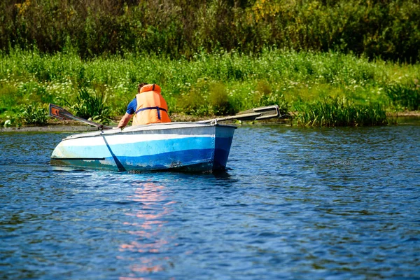 Mann in Schwimmweste rudert mit Boot über klares Wasser — Stockfoto